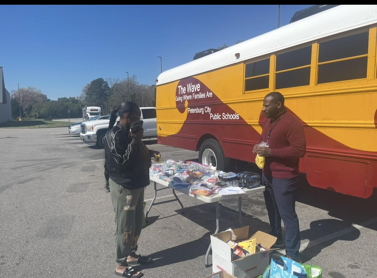 Community members distributing hygiene kits beside a school bus