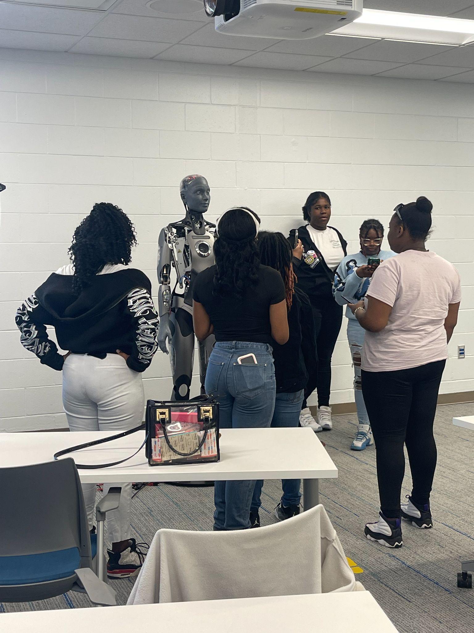 Builders Hub students gathered around Omni, a humanoid robot, at Richard Bland College