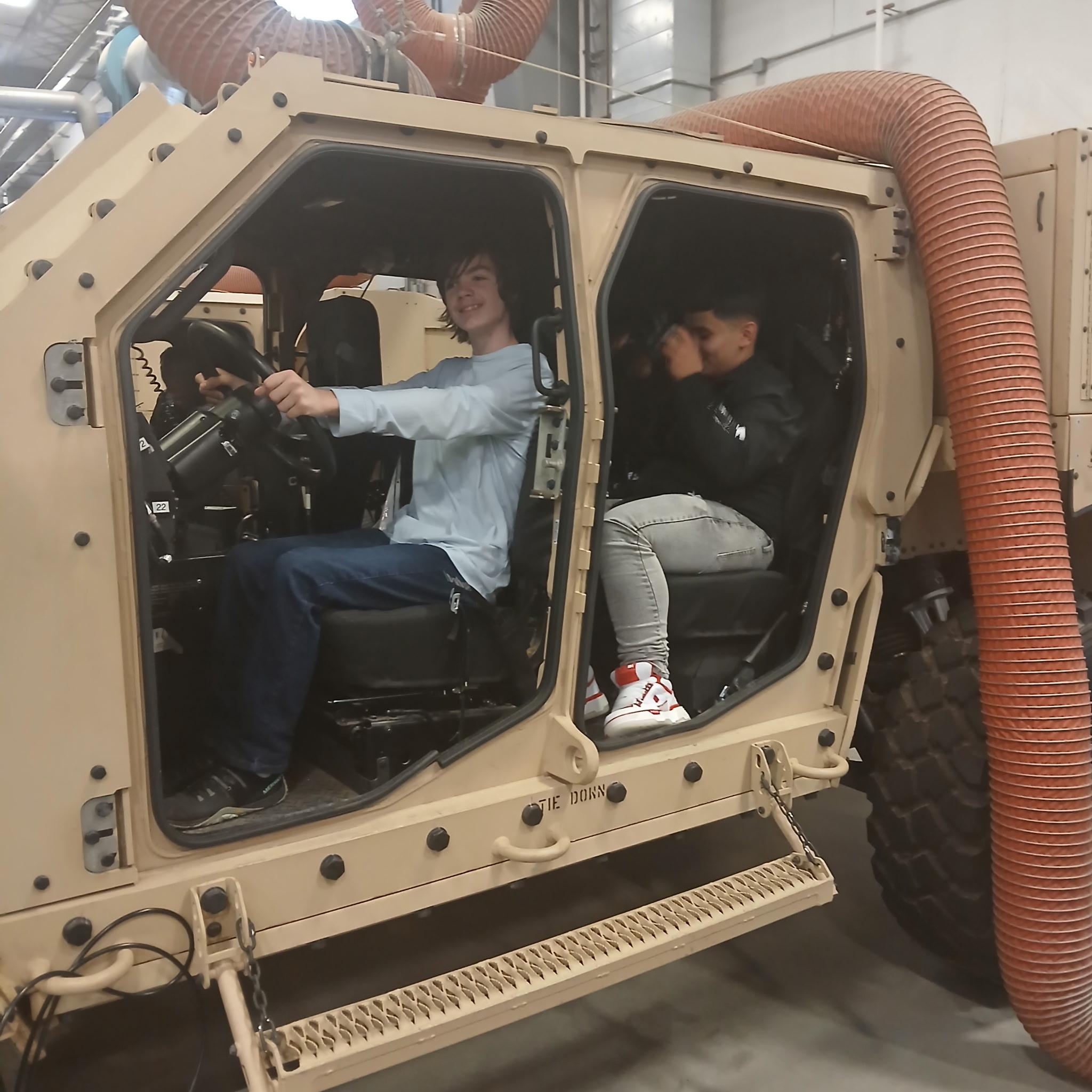 Builders Hub students exploring a military Humvee on the Enlisted day