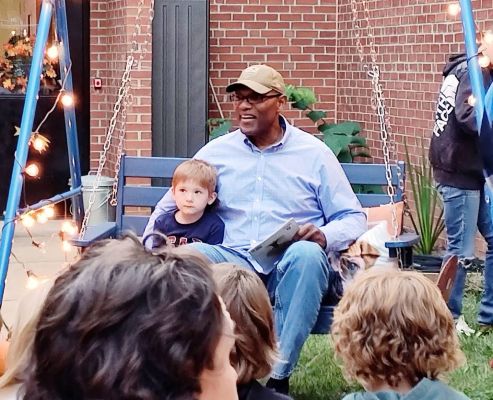 Children on a porch swing listening to a community read-aloud at Shenandoah Elementary
